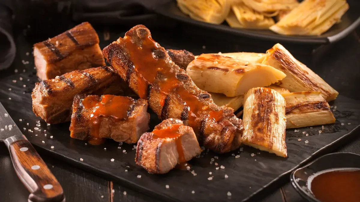 Costelinha na brasa com mandioca dourada e molho.