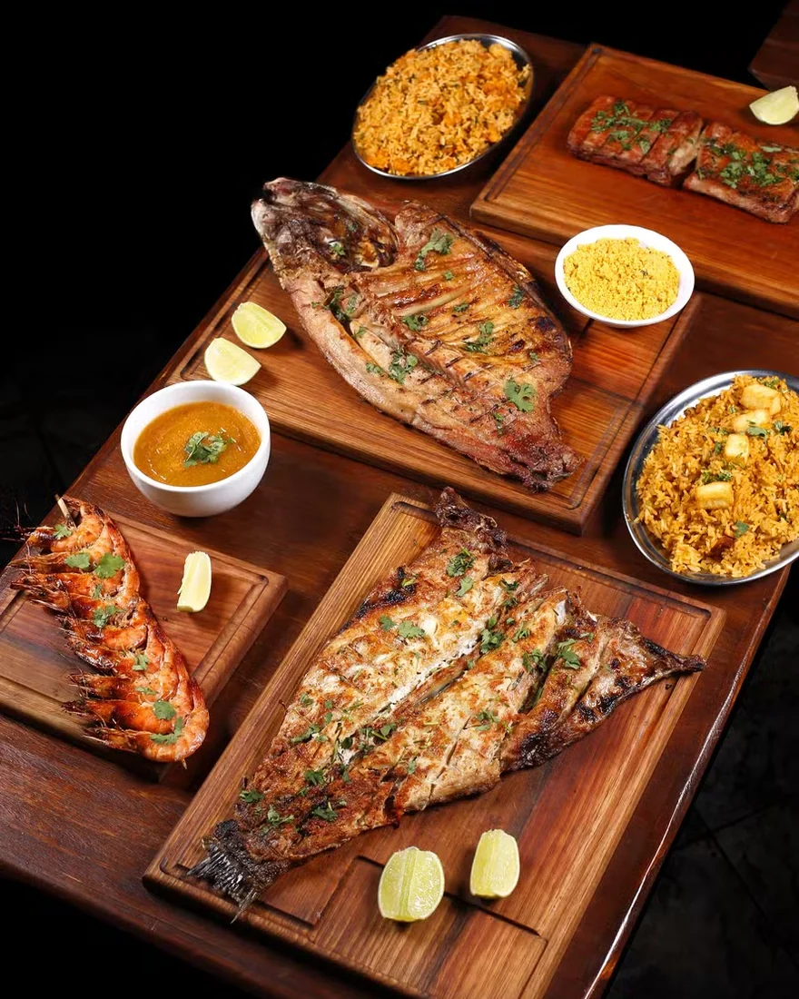 Peixes e frutos do mar grelhados sobre tábuas de madeira.
